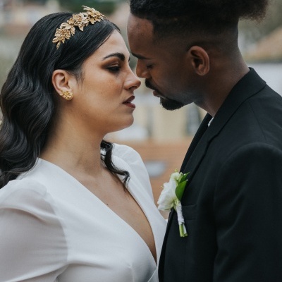 Casal próximo um do outro com roupa formal, mulher de branco, homem de preto.