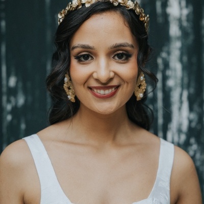 Mulher com diadema dourada floral, brincos grandes dourados e vestido branco