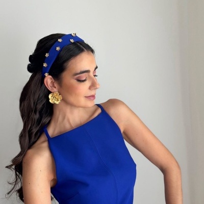 Mulher com vestido azul e acessórios dourados