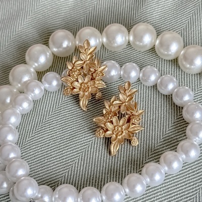 Colar e pulseira de pérolas brancas com peça dourada floral em tecido cinza