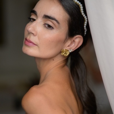 Mulher com faixa de cabelo com pérolas e brincos dourados florais