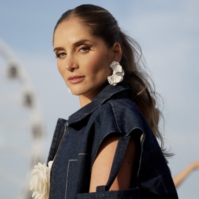 Mulher com brincos florais brancos e roupa de ganga azul escuro ao ar livre