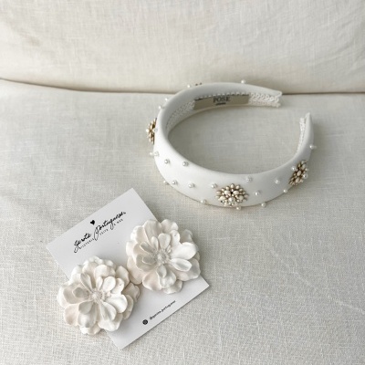 Tiara branca com pérolas e florais dourados ao lado de brincos florais brancos em tecido