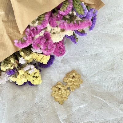 Brincos dourados florais e bouquet de flores secas coloridas