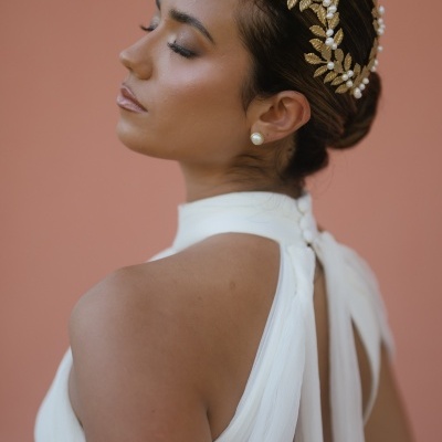Mulher com vestido branco e acessório dourado no cabelo
