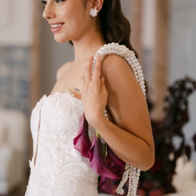 Mulher com vestido branco bordado e bolsa com alças de pérolas