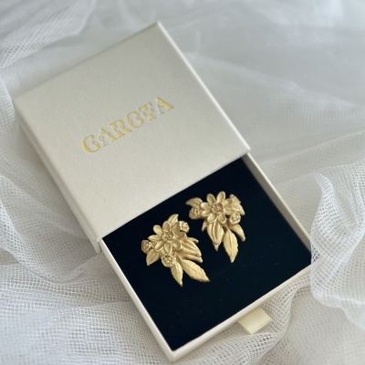 Brincos dourados em forma de flor numa caixa branca GAROFA com interior preto