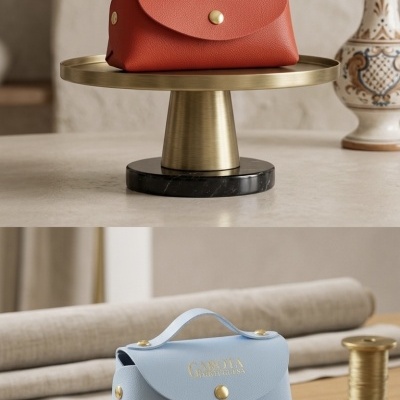 Duas bolsas de mão de pele vermelha e azul claro com texto dourado GAROTA PORTUGUESA, em superfícies elegantes, em ambiente decorado.