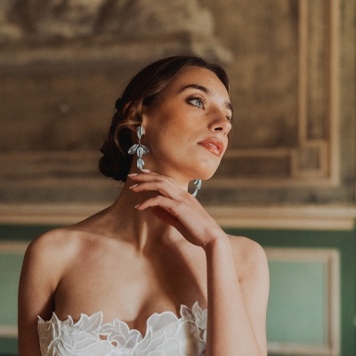 Mulher com vestido de noiva branco com detalhes florais em renda e brincos prateados