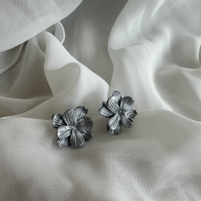 Brincos de flor prateados sobre tecido branco