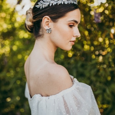 Mulher com tiara prateada e vestido branco em ambiente ao ar livre