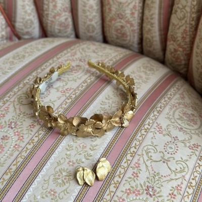 Tiara e brincos dourados com design floral sobre sofá estofado padrão floral