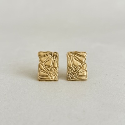 Brincos dourados com padrão floral texturizado em relevo