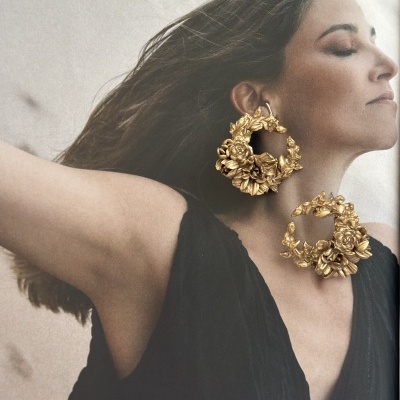 Brincos dourados grandes em formato circular com detalhes florais