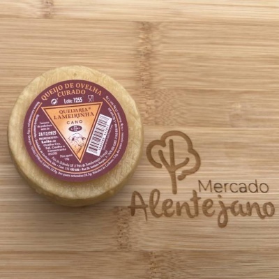 Queijo de ovelha curado com etiqueta colorida sobre superfície de madeira gravada Mercado Alentejano