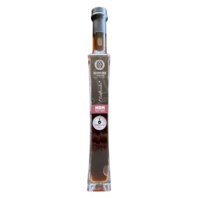 Garrafa de vidro alta com líquido castanho e rótulo SEGREDOS TRADICIONAIS MDM