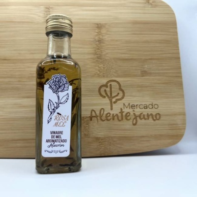 garrafa de vinagre aromatizado de mel e alecrim com rótulo branco e desenho de rosa sobre tábua de madeira