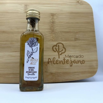 Frasco de vinagre de mel aromatizado com tomilho com rótulo branco em tábua de madeira gravada