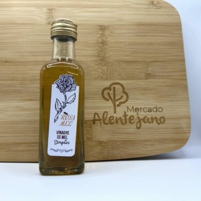 Frasco de vinagre de mel com etiqueta branca e tábua de madeira com gravação