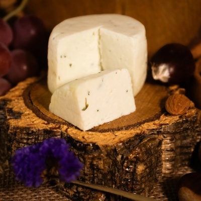 Queijo branco com ervas sobre base de madeira com avelãs, castanhas e uvas