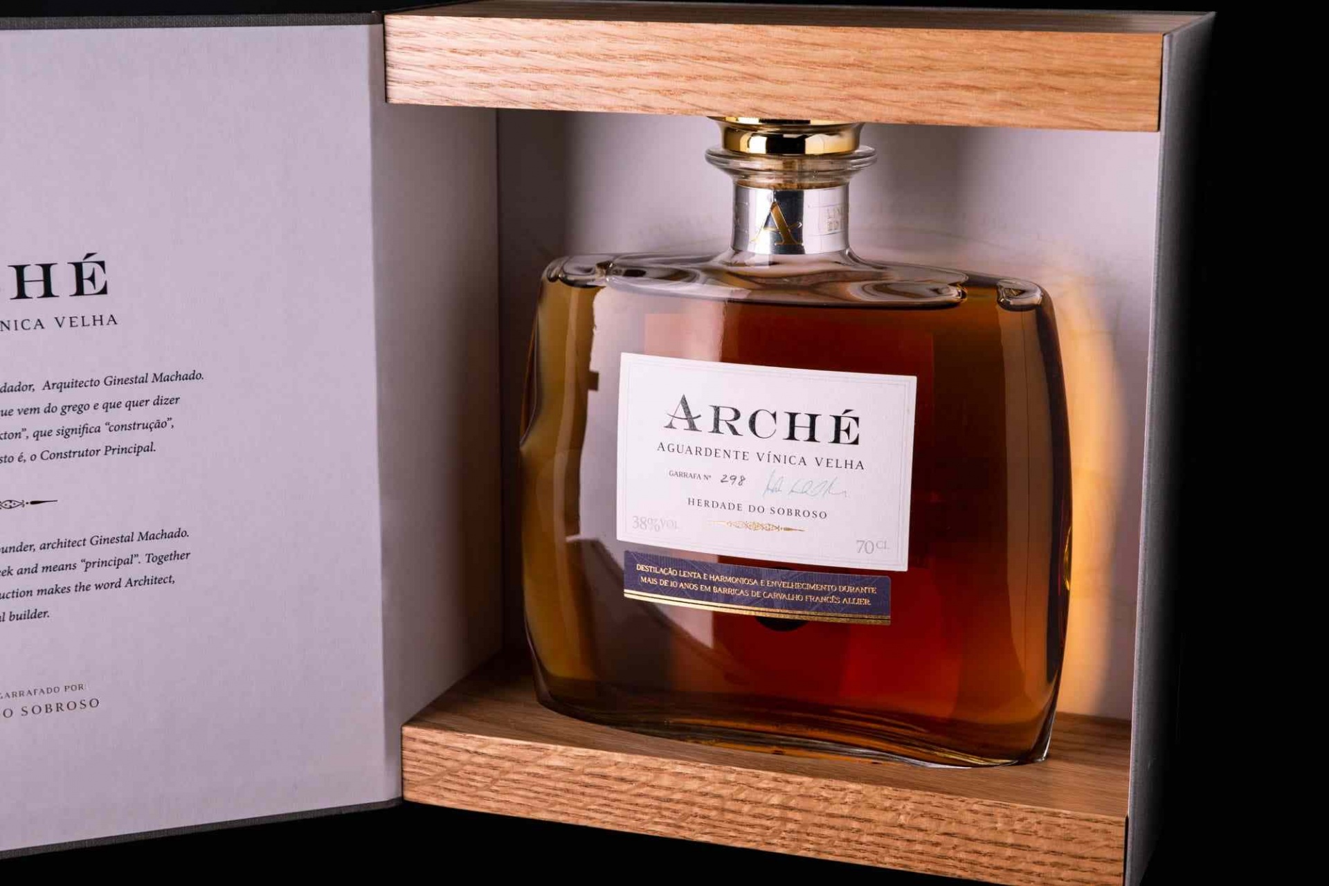 Aguardente Velha Arche Herdade do Sobroso Garrafa com líquido castanho numa caixa aberta de madeira clara