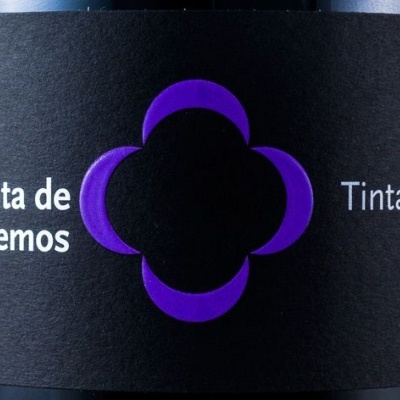Rótulo preto de vinho com texto branco e logótipo roxo