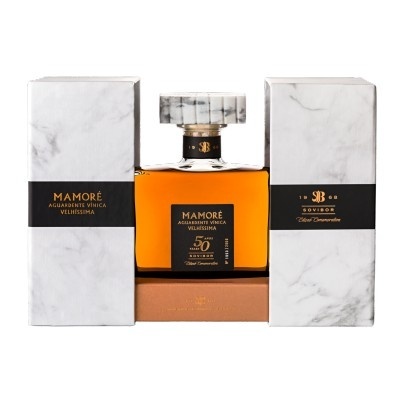 Garrafa quadrada com licor âmbar e tampo marmoreado entre caixas marmoreadas