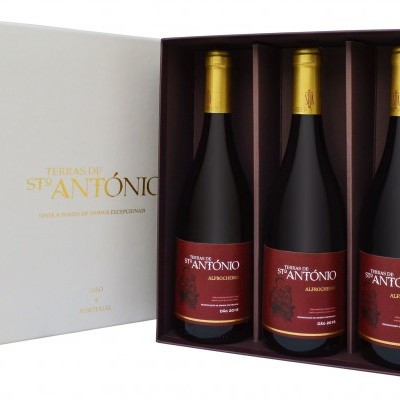 Conjunto de três garrafas de vinho tinto em caixa branca com texto dourado