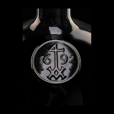 Garrafa preta com selo circular em relevo e números 1692