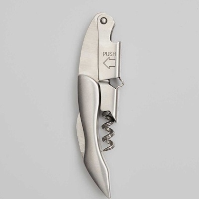 Saca-rolhas de inox prateado com inscrição PUSH e seta sobre fundo cinza