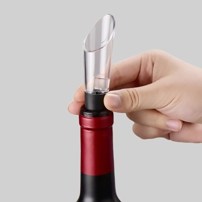 Saca-rolhas transparente e preto numa garrafa de vinho com rótulo vermelho