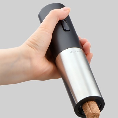 Abridor eléctrico de vinho com acabamento em aço inoxidável e preto, segurado por uma mão