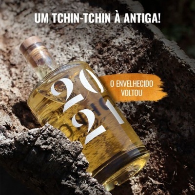 Garrafa de bebida envelhecida 2021 em tronco de madeira com texto promocional