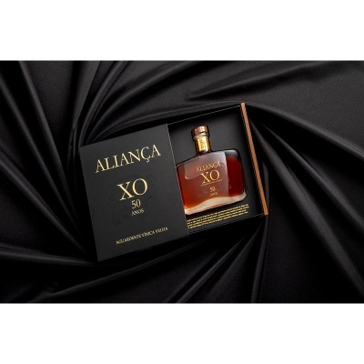Caixa preta com garrafa de aguardente Aliança XO 50 anos sobre tecido preto
