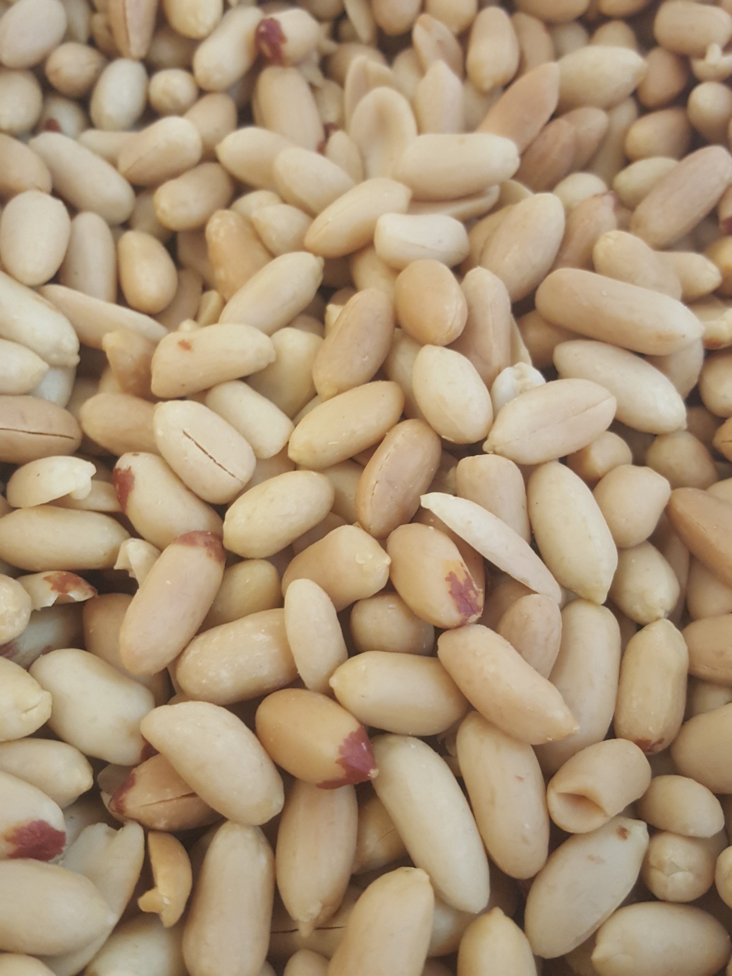 Amendoins descascados bege claro com pontas castanhas-rosadas