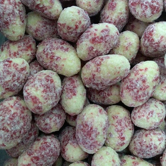 Amendoins cobertos por camada granulada verde e vermelha com textura irregular