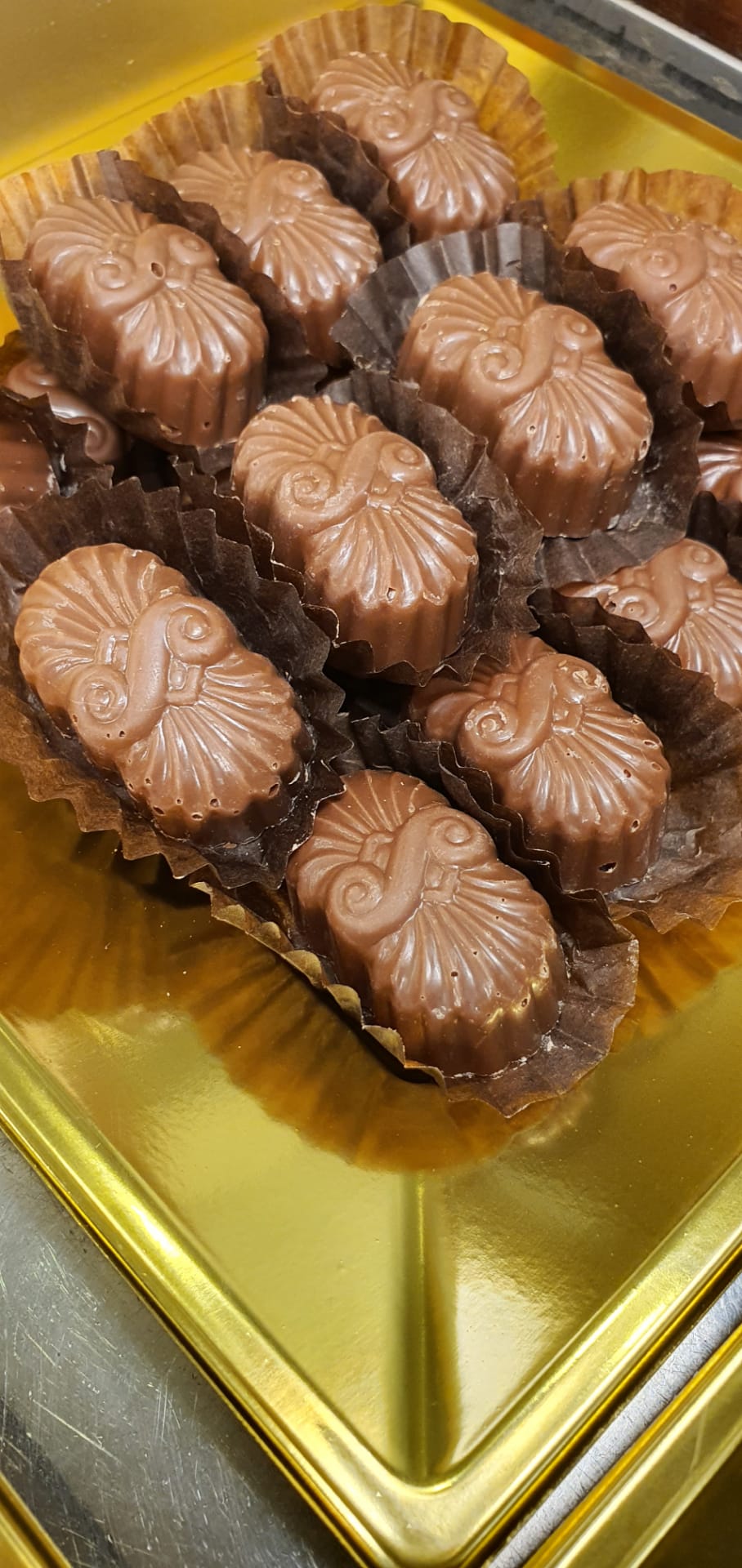 Bombons de chocolate com forma de conchas em bandeja dourada