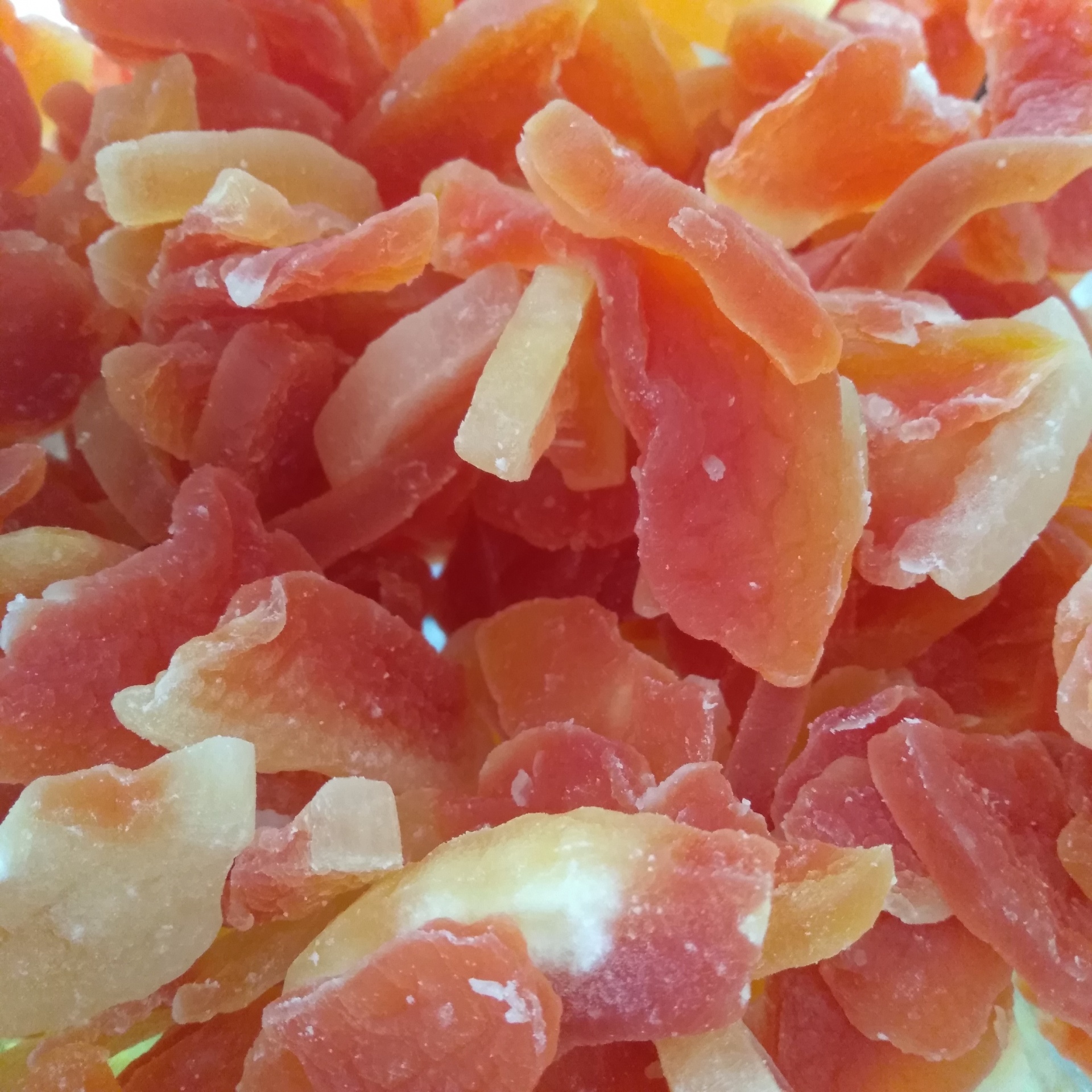 Frutas secas coloridas em tons de laranja, amarelo e vermelho, texturas rugosas, sobre fundo claro