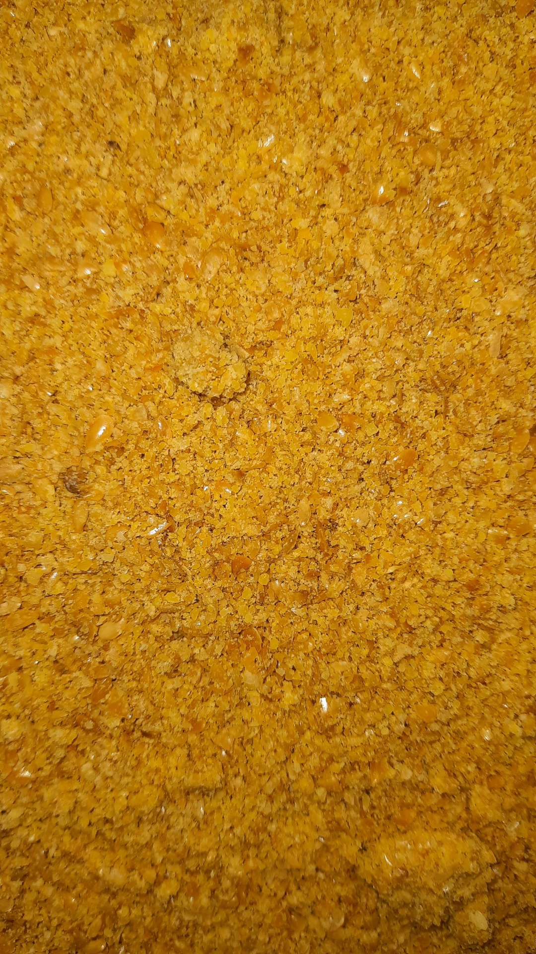 Produto alimentar granulado amarelo alaranjado semelhante a farelo de milho