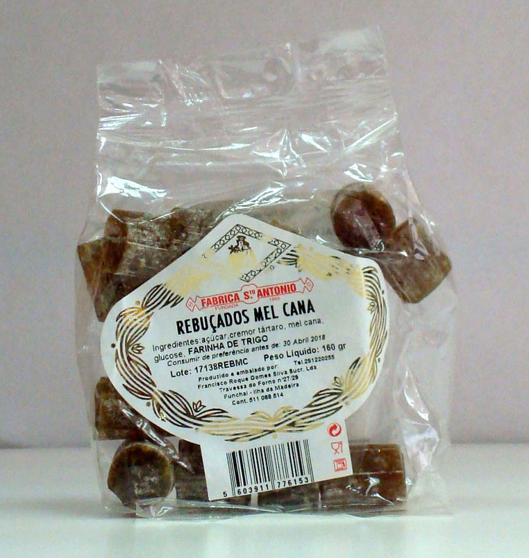 Pacote transparente com rebuçados castanhos e rótulo branco com texto