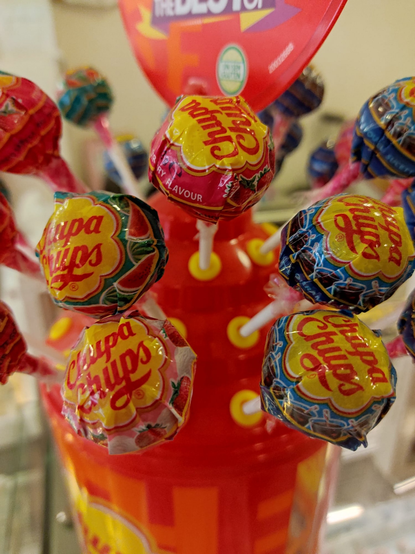 Pirulitos Chupa Chups coloridos num suporte vermelho com amarelo