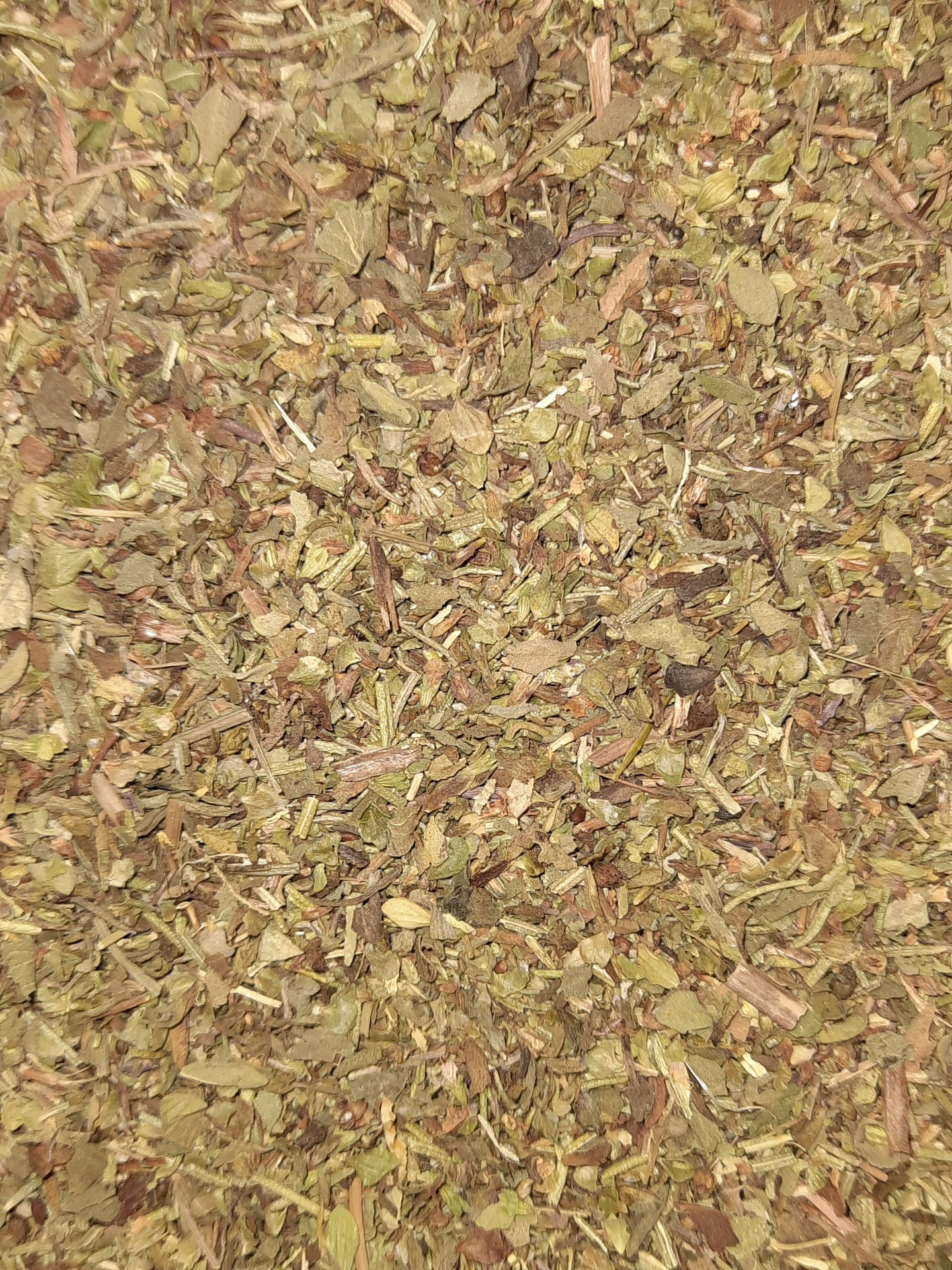 Mistura de ervas secas em tons verdes e castanhos com textura irregular.