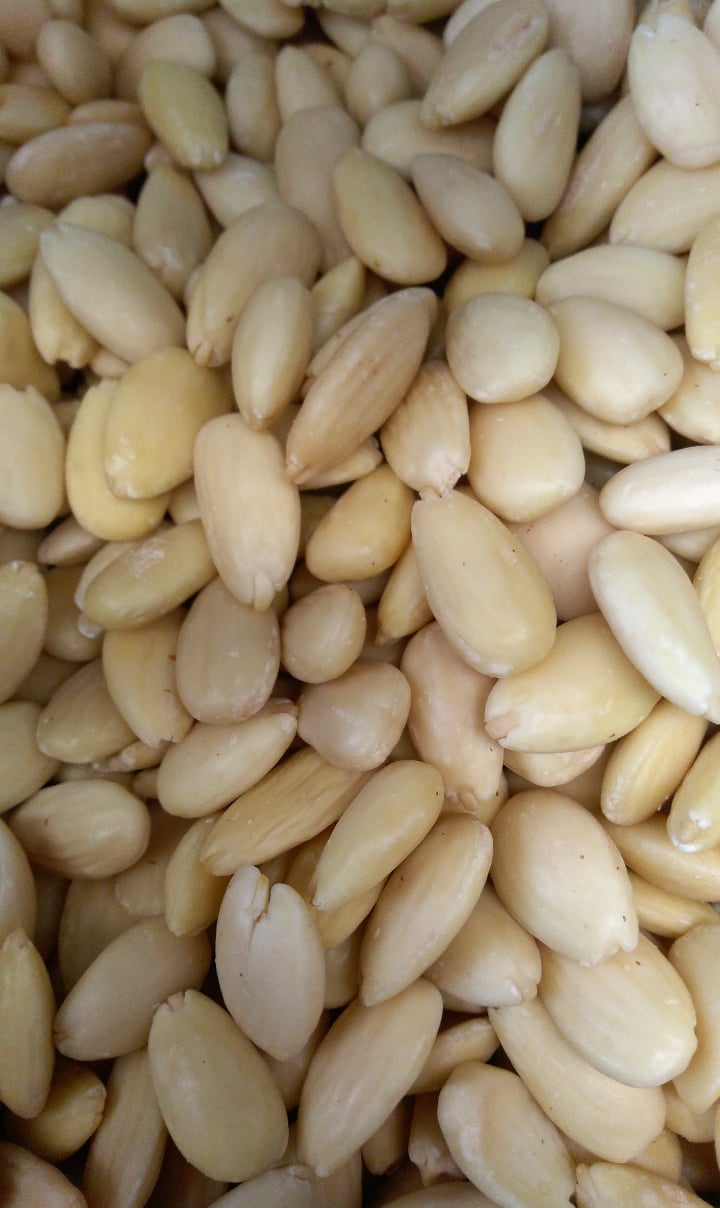 Amêndoas descascadas em close-up, textura lisa, cor creme clara.