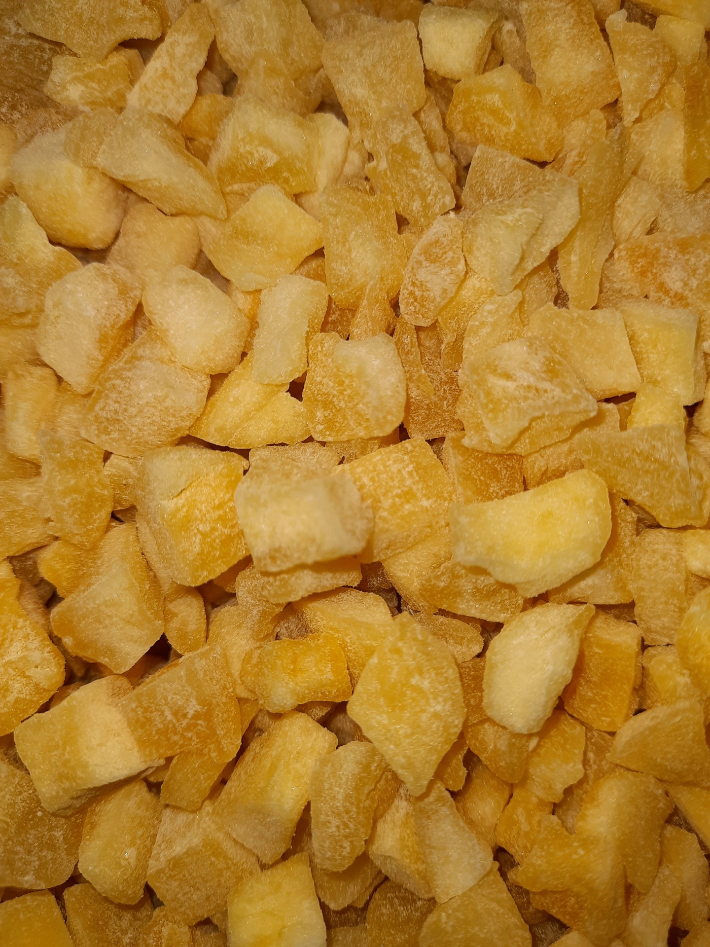 Pedaços pequenos de fruta desidratada amarela e castanha com textura seca e rugosa