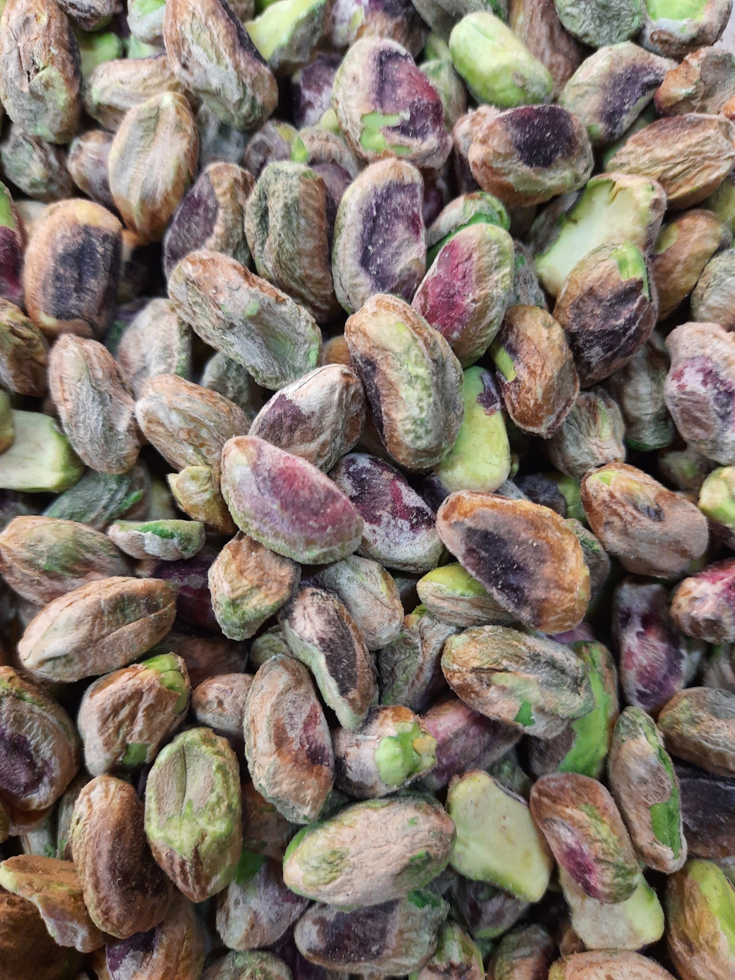 Pistáchios descascados com cores verde, roxo e castanho e textura rugosa