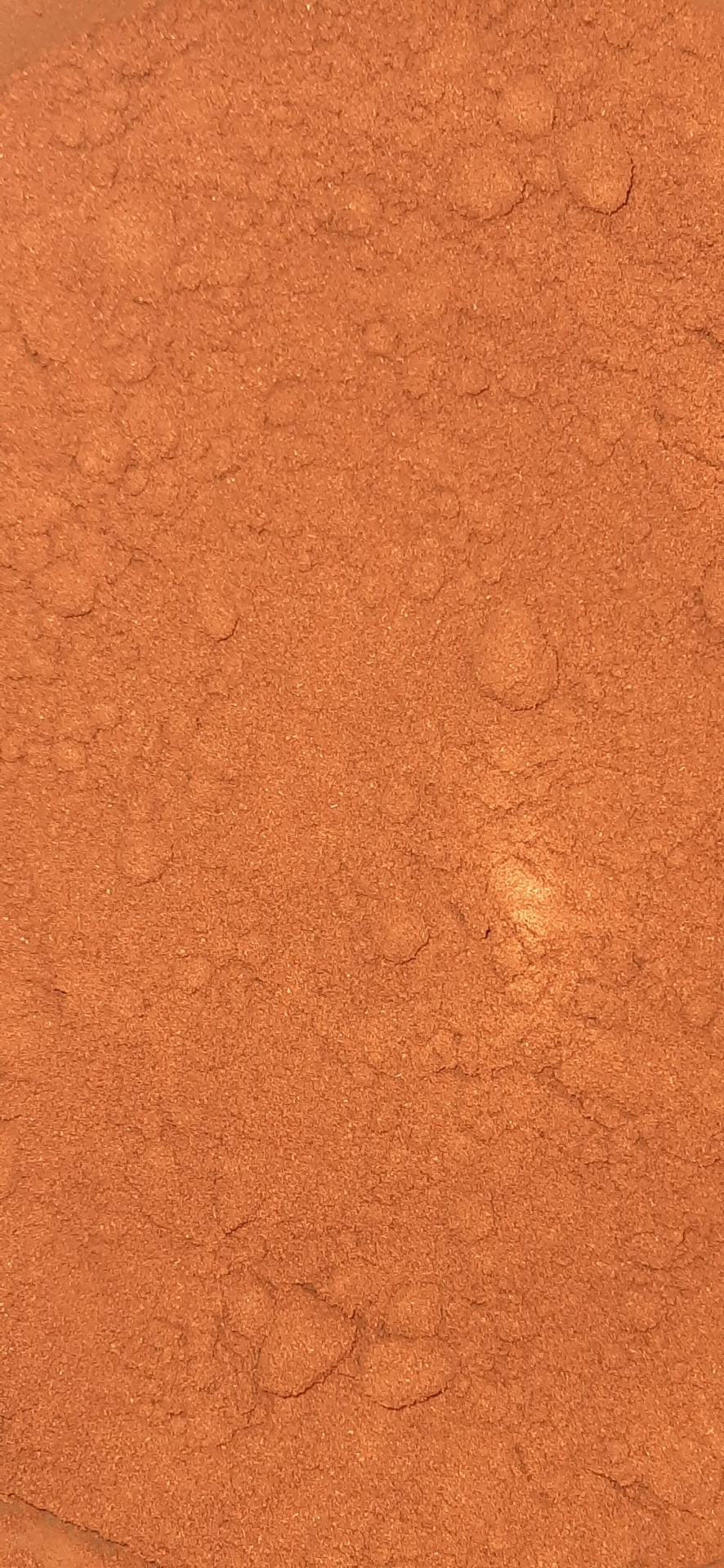 Pó fino de cor castanho avermelhada com textura irregular