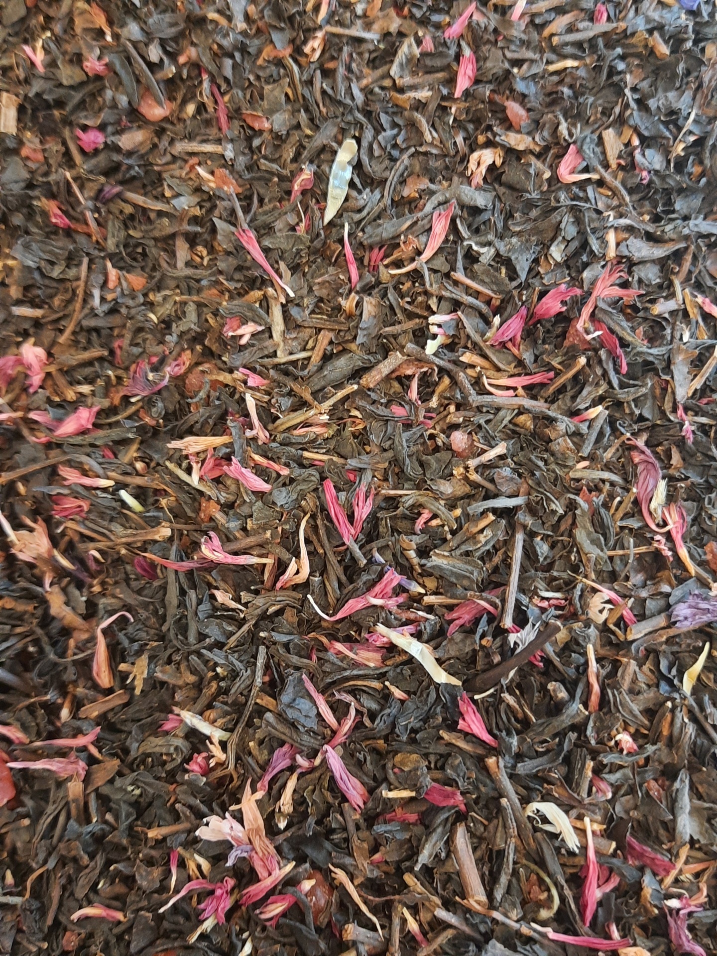 Folhas de chá preto com pétalas secas vermelhas e brancas