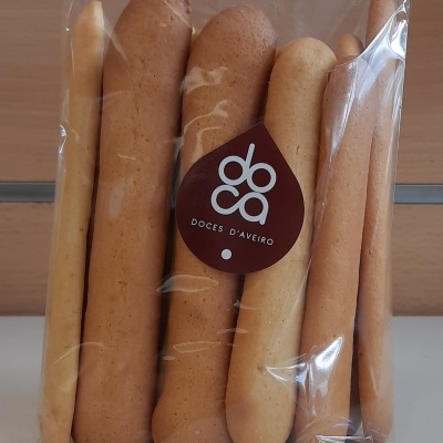 Pacote transparente com palitos de pão de várias cores e etiqueta preta com texto DOCA DOCES D'AVEIRO