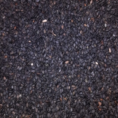 Sementes pretas pequenas com textura rugosa e algumas sementes castanhas e brancas