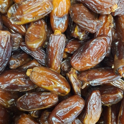 Tâmaras secas castanho-escuro a castanho-claro com textura brilhante e rugosa, empilhadas